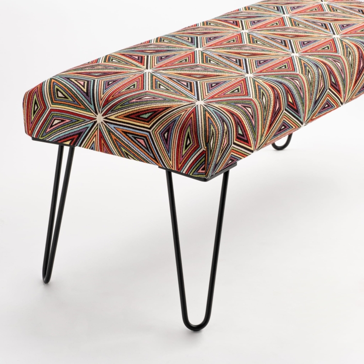 Banco tapizado con estampado sobre patas de metal, perfecto para interiores industriales