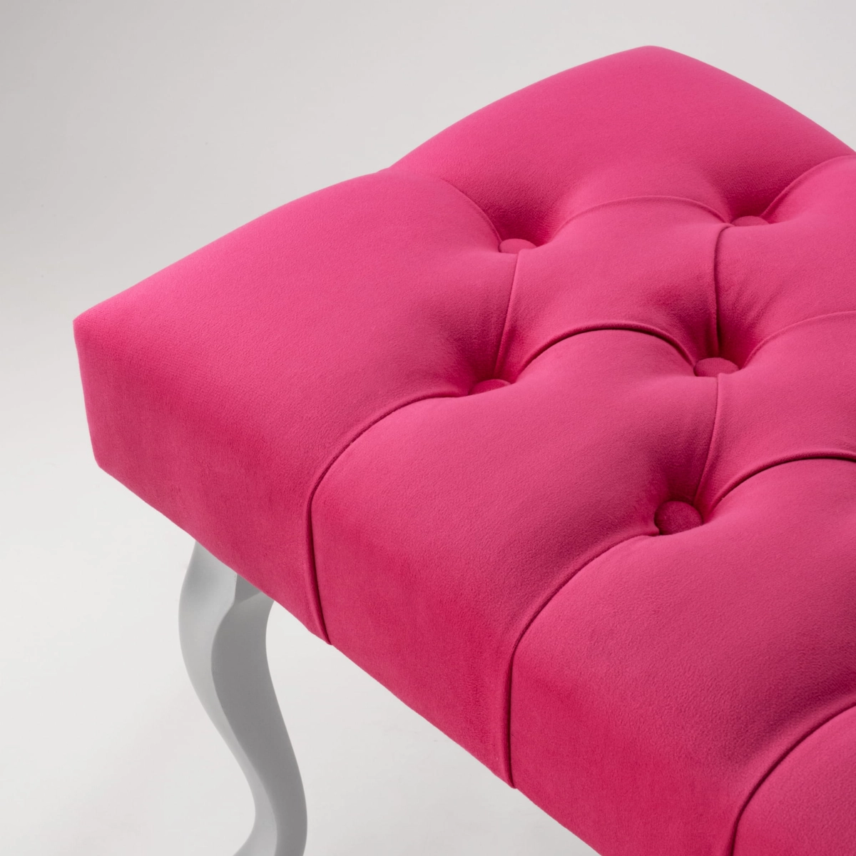 Elegante banco fucsia con mechones y patas de metal plateado, perfecto para una sala de estar o un vestidor.