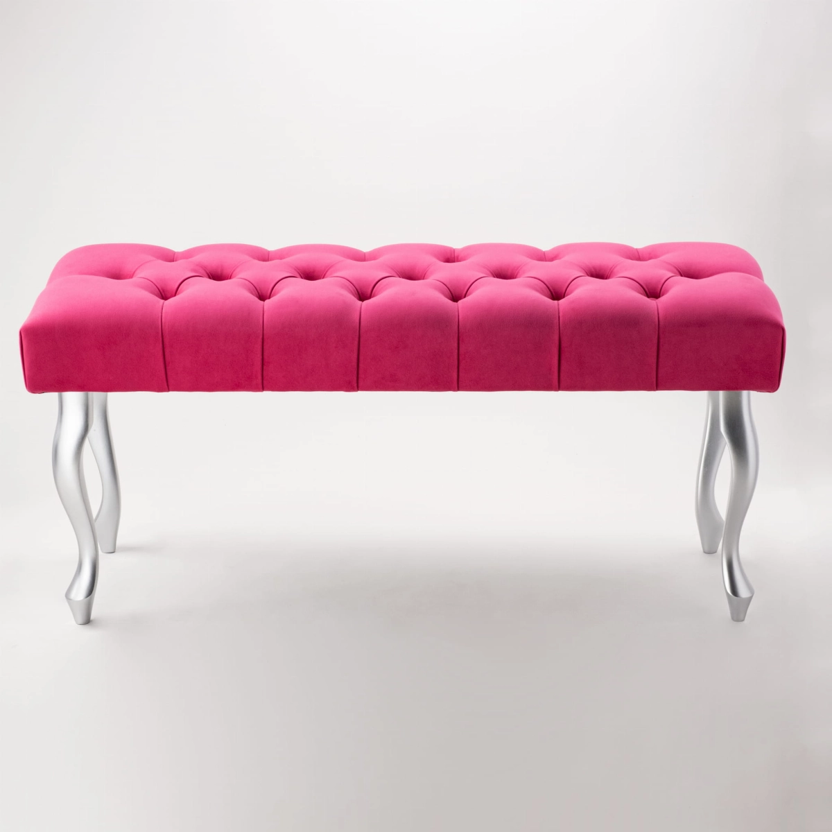 Un elegante banco acolchado en un intenso color fucsia con patas plateadas