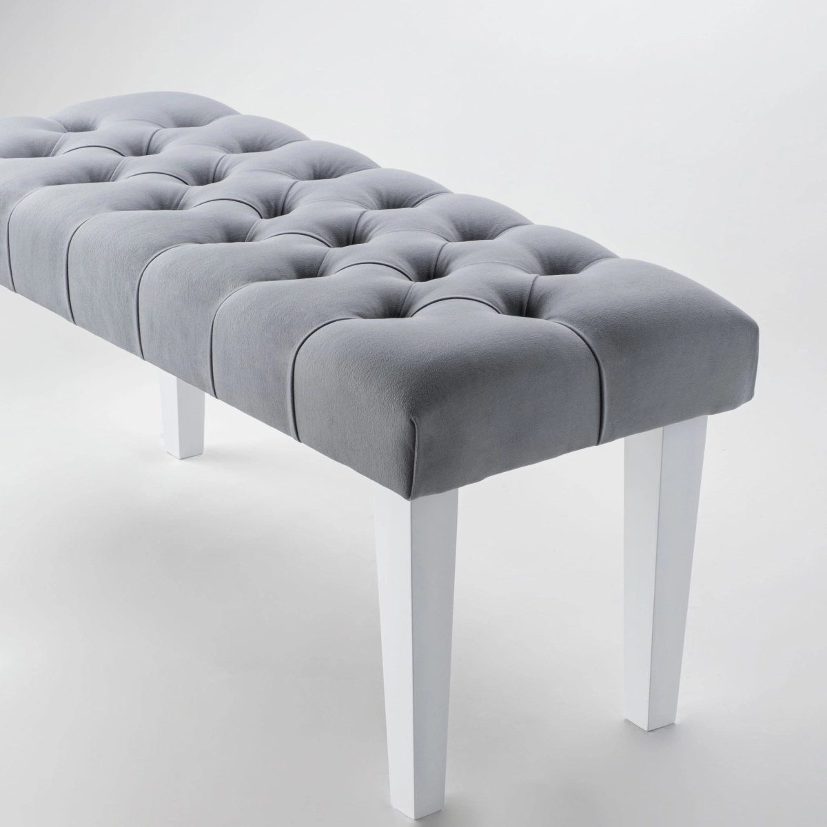 Elegante banco gris con tapizado acolchado y patas blancas