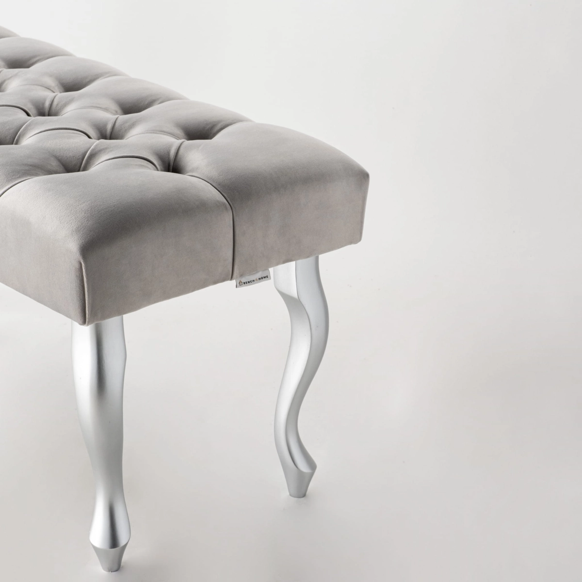 Banco tapizado en gris con patas de metal plateado