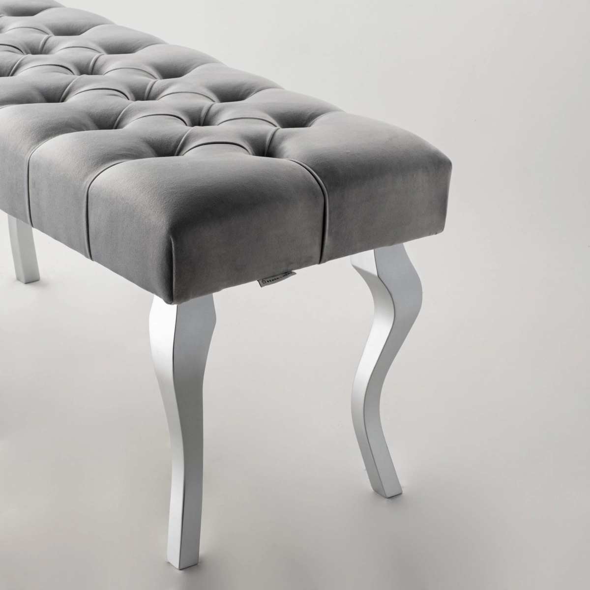 Banco gris acolchado con patas cromadas brillantes