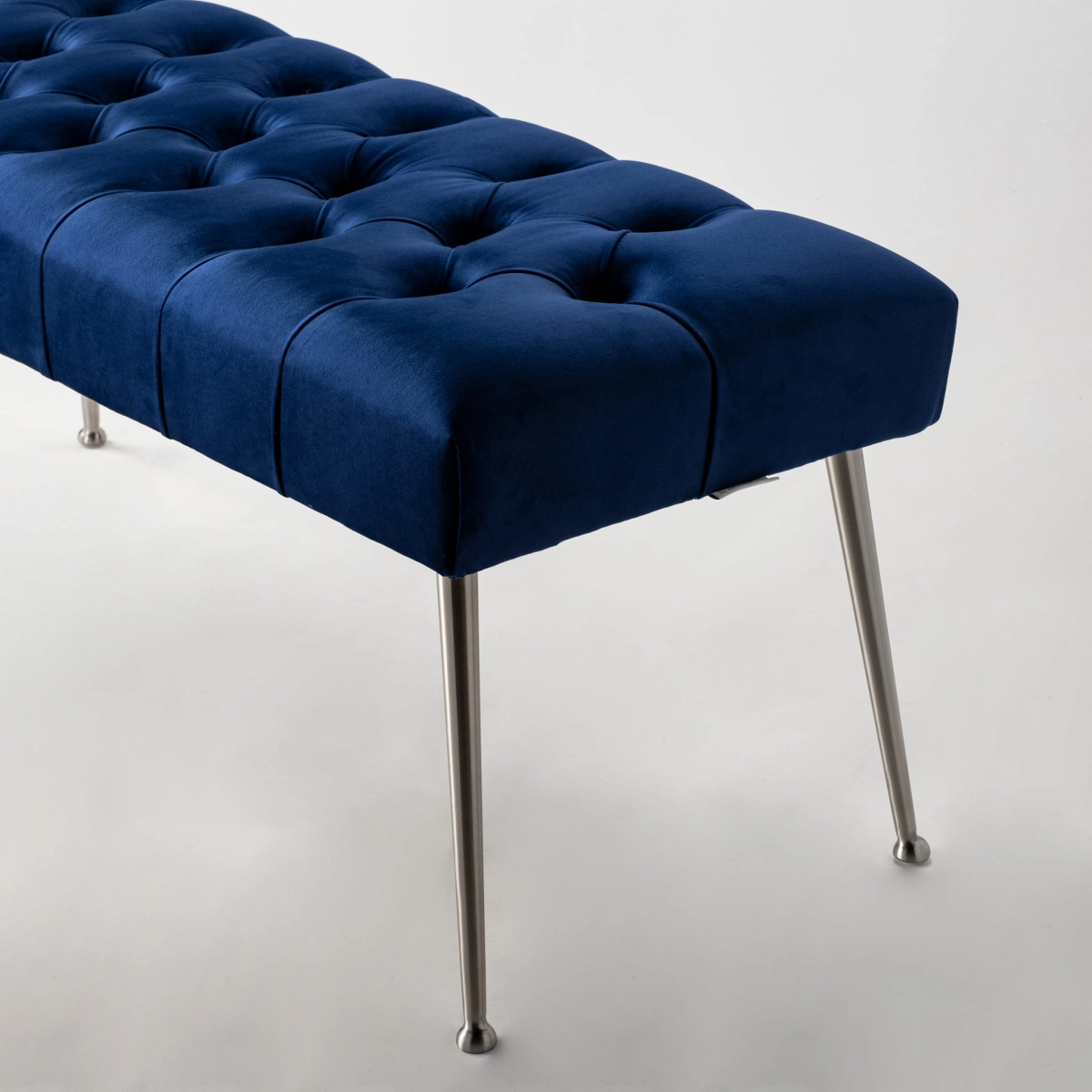 Banco acolchado azul marino con patas de metal, perfecto para interiores estilo loft