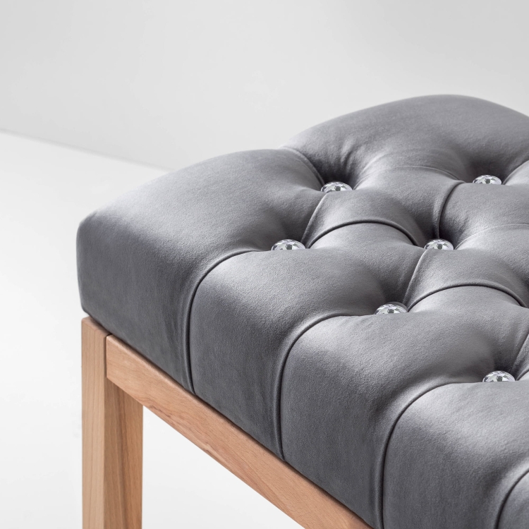 Elegante banco de pasillo con asiento acolchado gris y un práctico estante