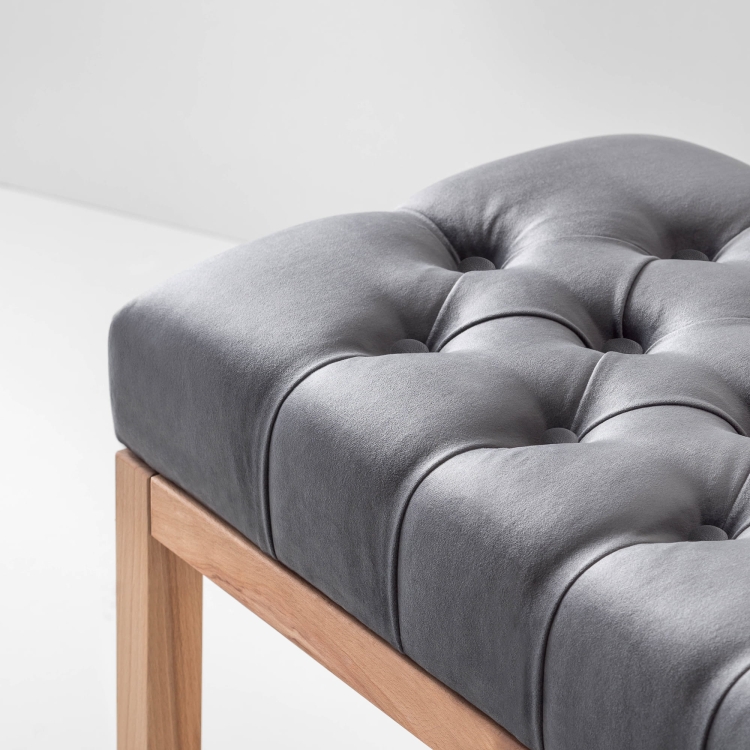 Banco tapizado gris acolchado con estructura de madera y estante inferior